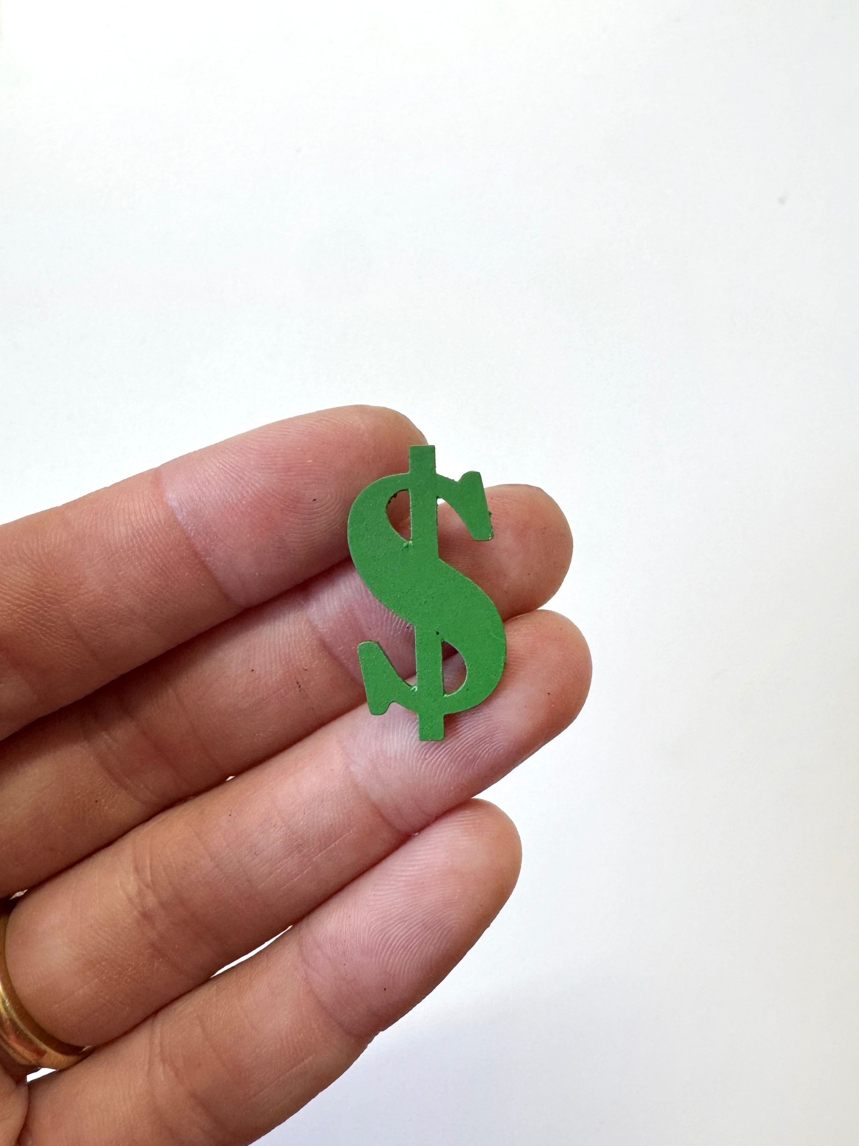 A small green dollar sign magnet  held between a person&